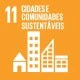 A imagem representa o Objetivo de Desenvolvimento Sustentável (ODS) 11 – Cidades e Comunidades Sustentáveis. O fundo é laranja, no canto superior esquerdo está o número 11, acompanhado do texto em branco “Cidades e Comunidades Sustentáveis”. No centro, há ícones de edificações em branco, incluindo uma casa, prédios e construções variadas, simbolizando o planejamento urbano sustentável e o desenvolvimento de comunidades mais inclusivas e resilientes.